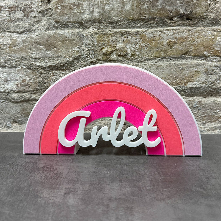 Arcoíris de colores a elegir con el nombre personalizados, fabricado en impresión 3D con material biodegradable con tres colores a elegir y con el nombre de la persona delante en color blanco. 